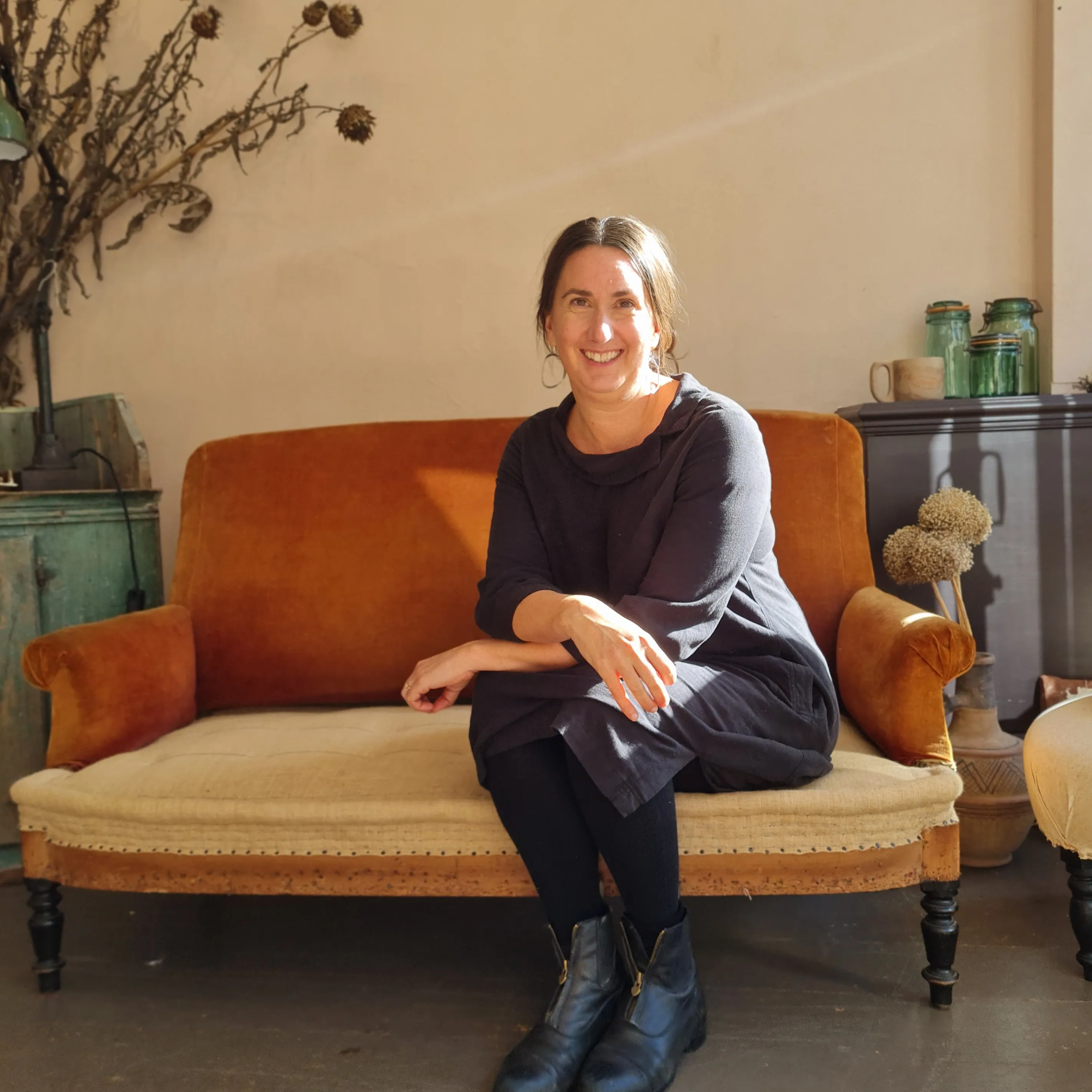 Clare Burke, smiling, seated on an orange sofa