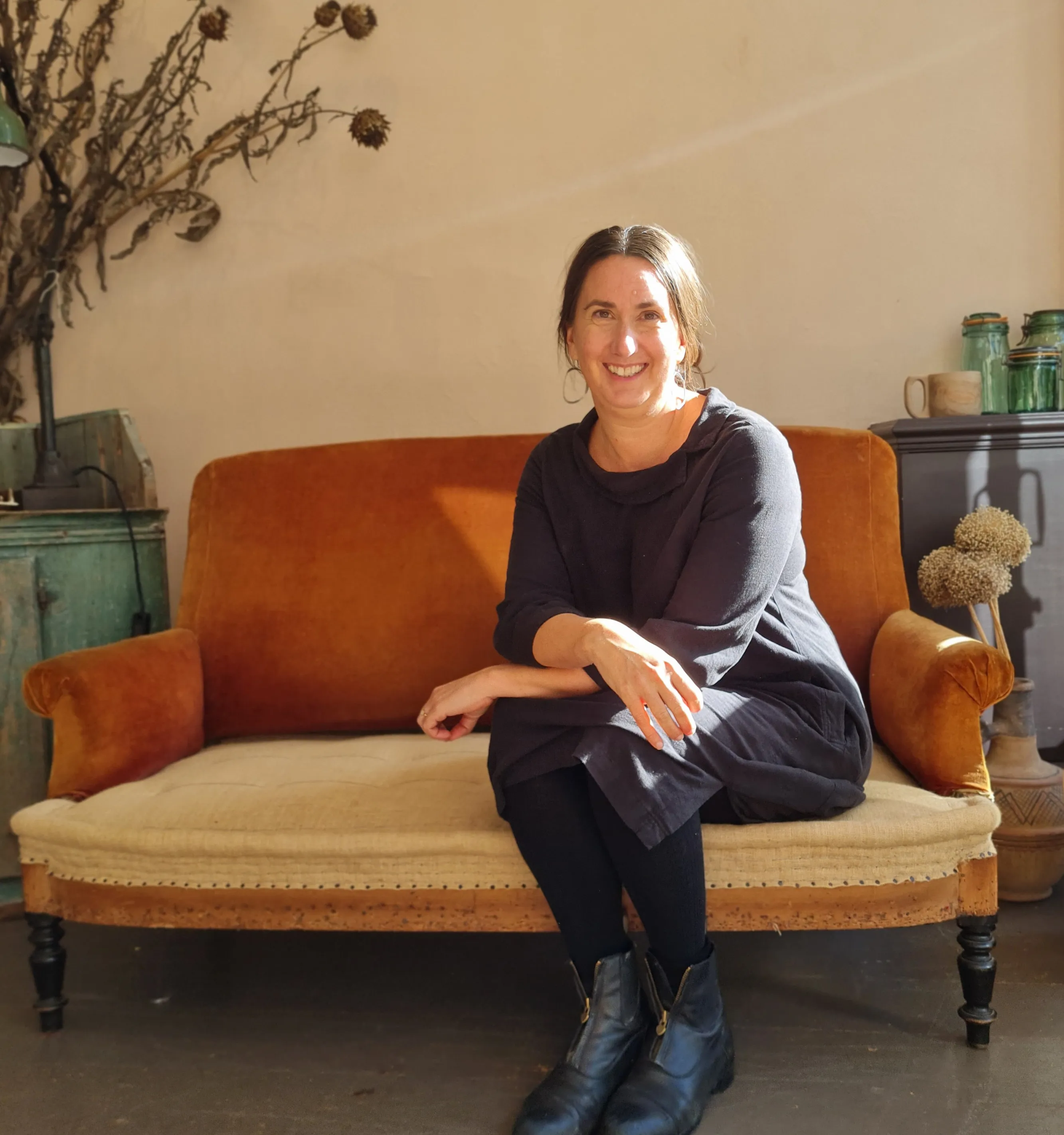 Clare Burke sitting on an orange sofa, smiling.